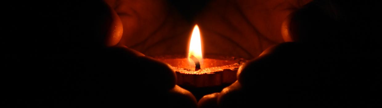 Warm candlelight cupped by hands