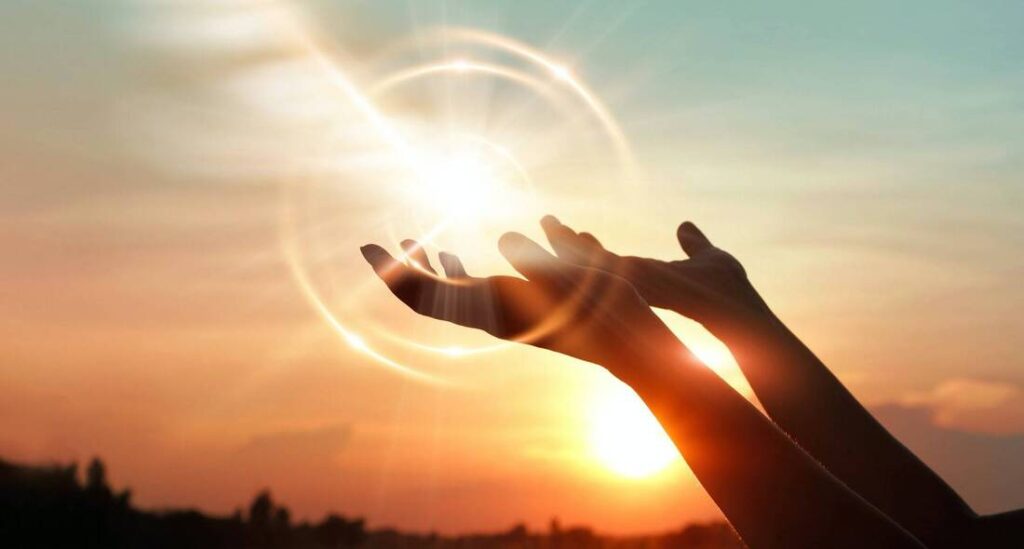 Spiritual hands embracing the sun's energy