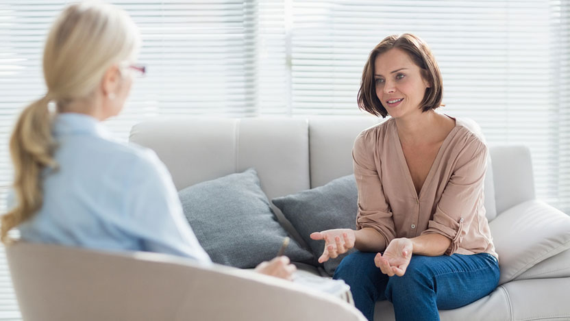 Woman conversing with therapist on sofa